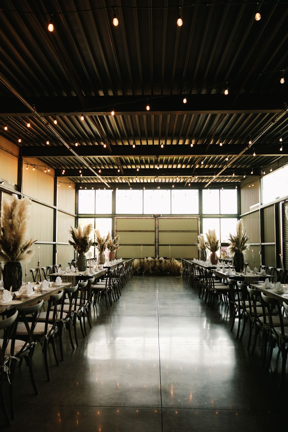 Modern event space interior with industrial ceiling and large windows.