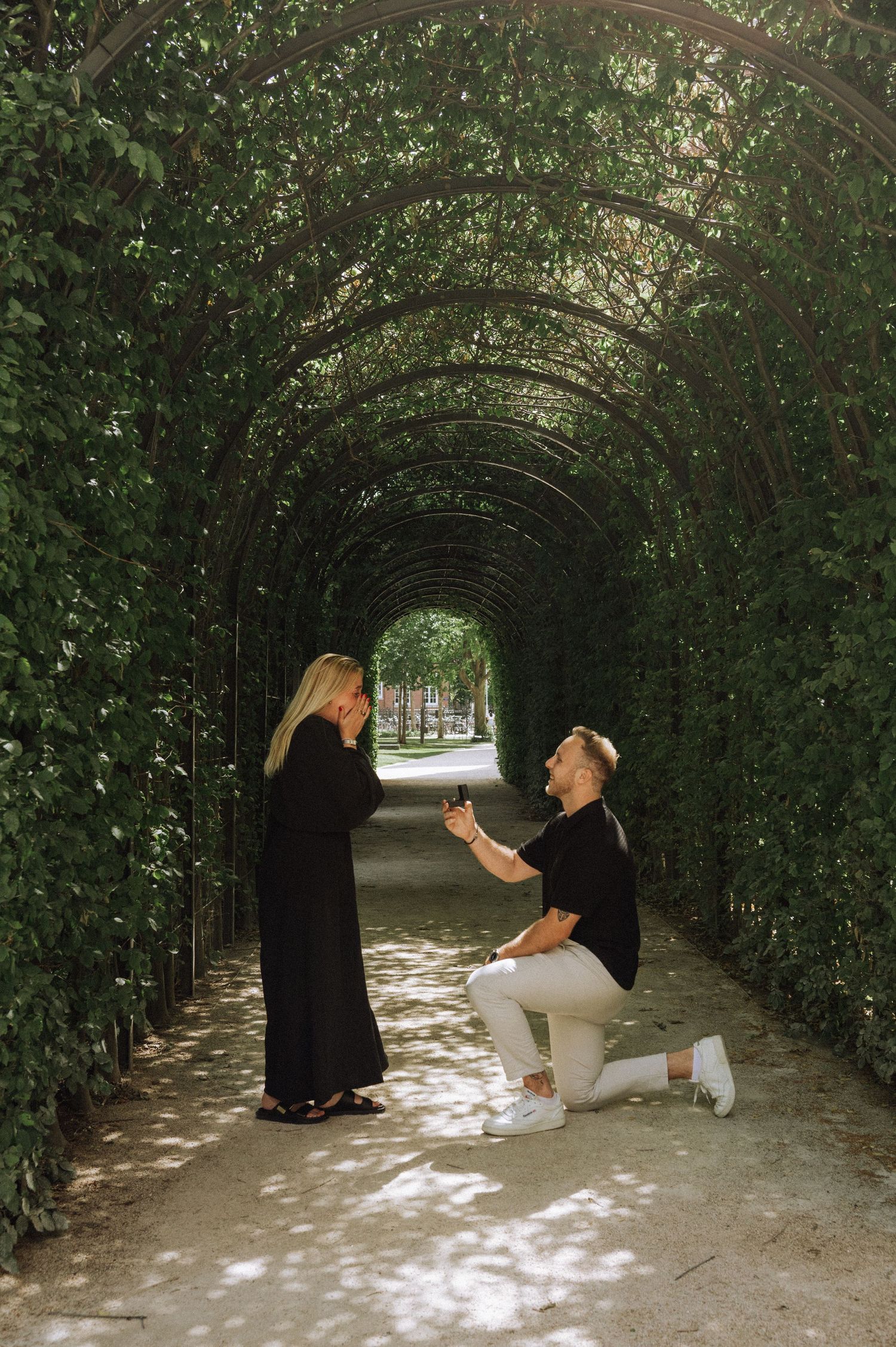 Romantic couple in the Rijksmuseum Gardens after their secret proposal in Amsterdam.