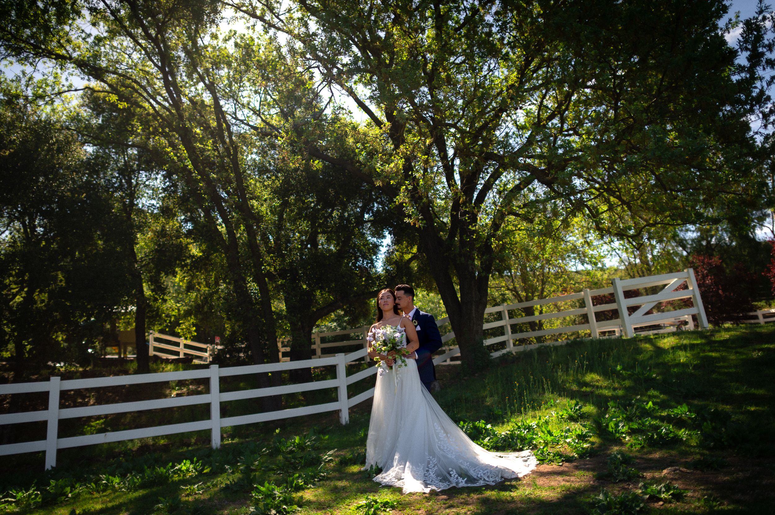 A scenic garden wedding venue with white picket fences and towering trees.