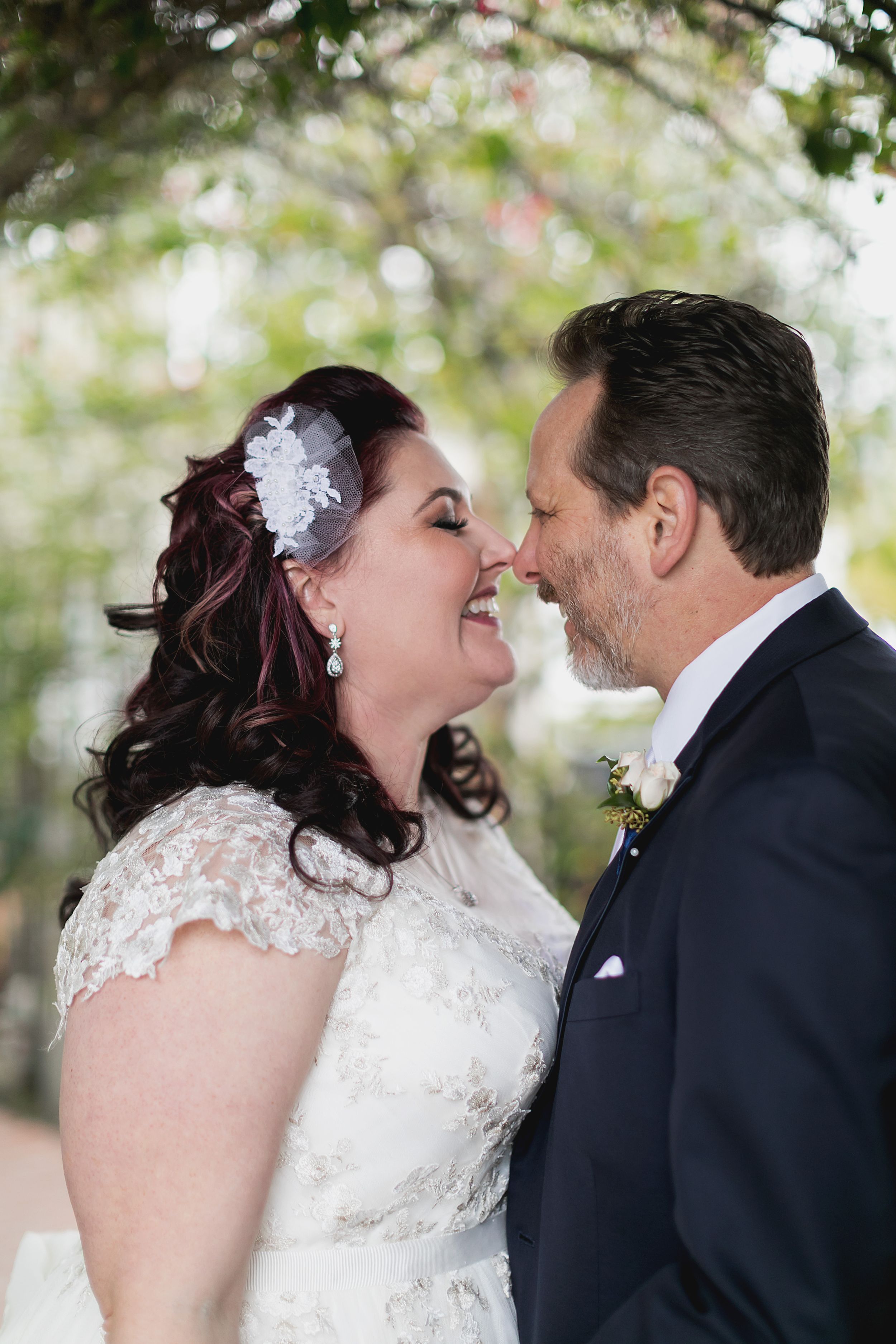 A joyful wedding moment captured as the couple laughs together under garden trees.