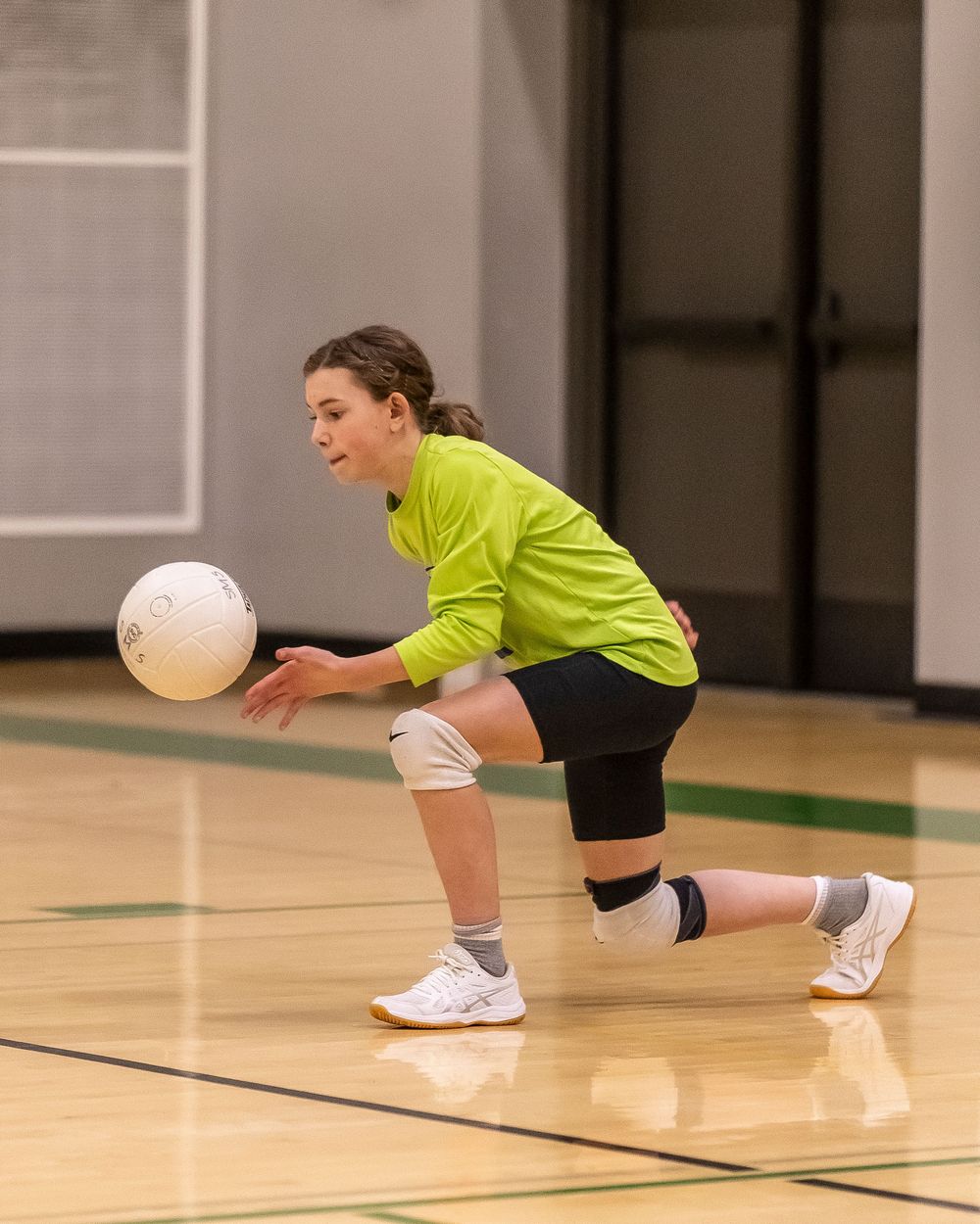 Action sports photography. Image of a young lady playing volleyball about to serve the ball.