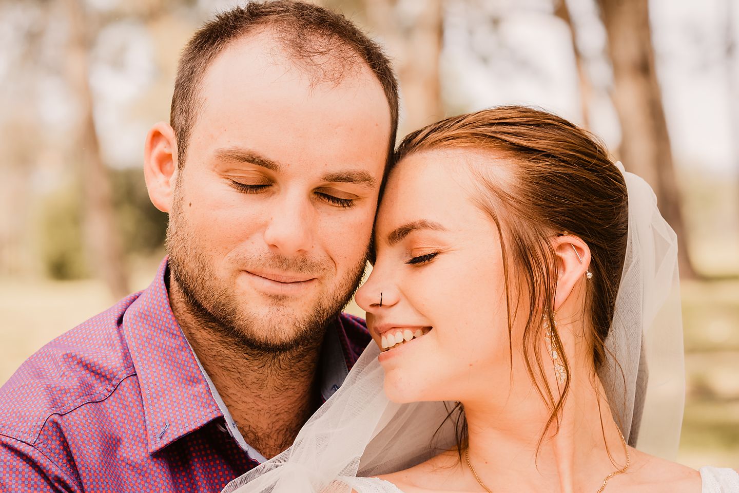 A romantic couple shares tender moments in a natural outdoor setting during an engagement photo session.