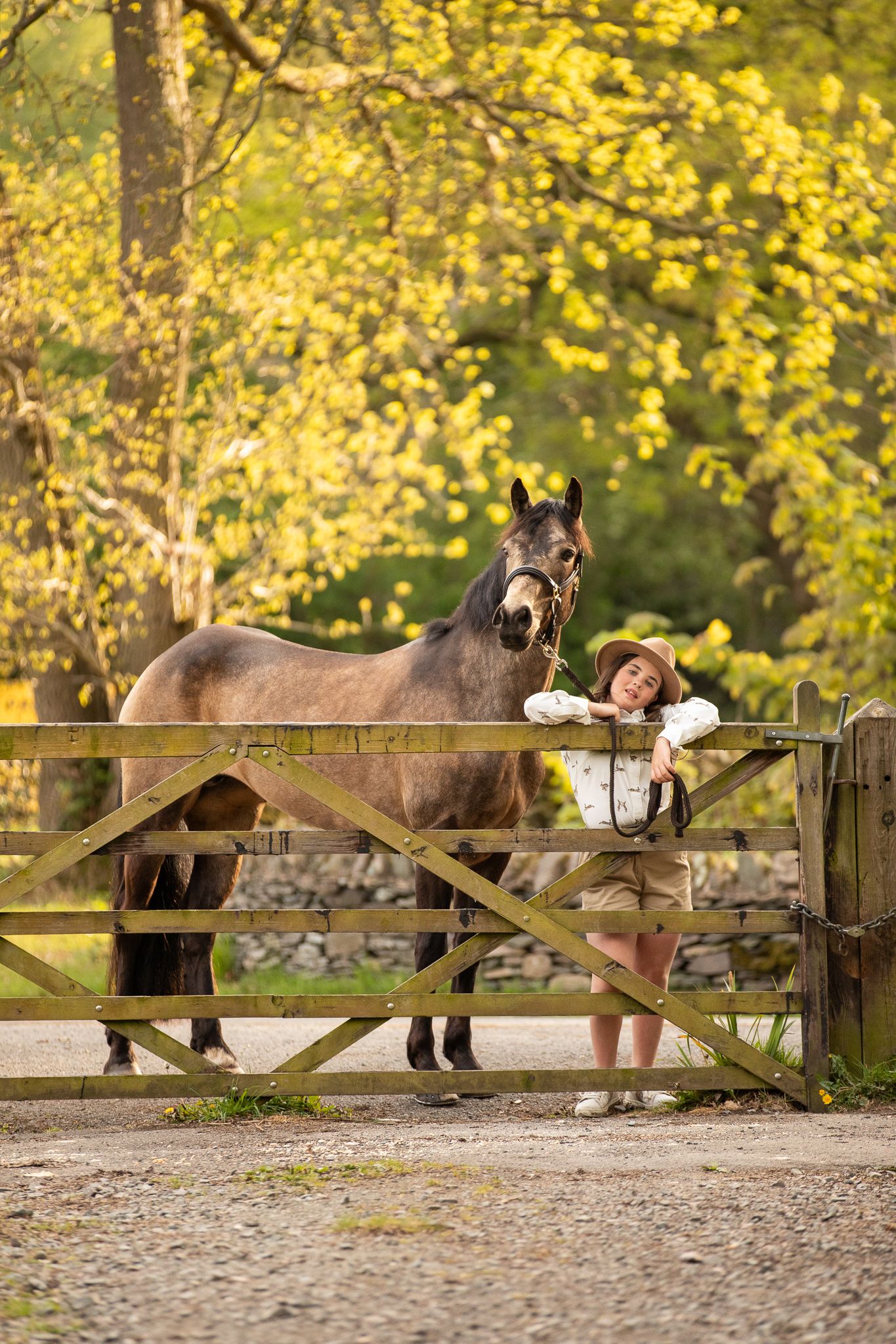 Young equestrian poses with palomino pony in a series of natural outdoor portraits showing their special bond.