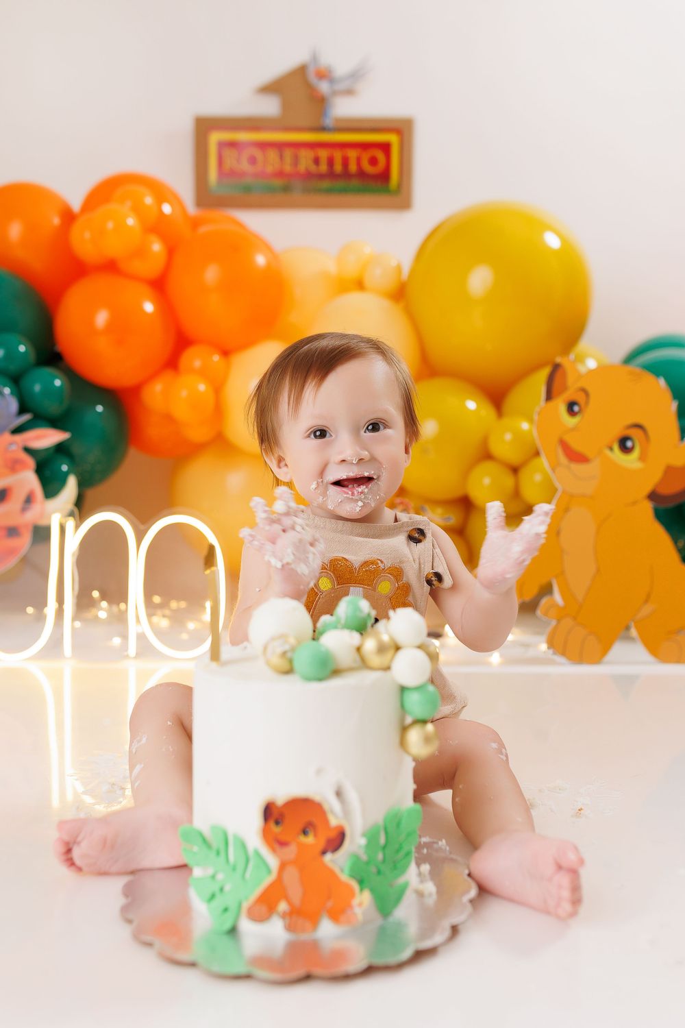 Dinosaur themed cake smash photography session with colorful balloon garland.