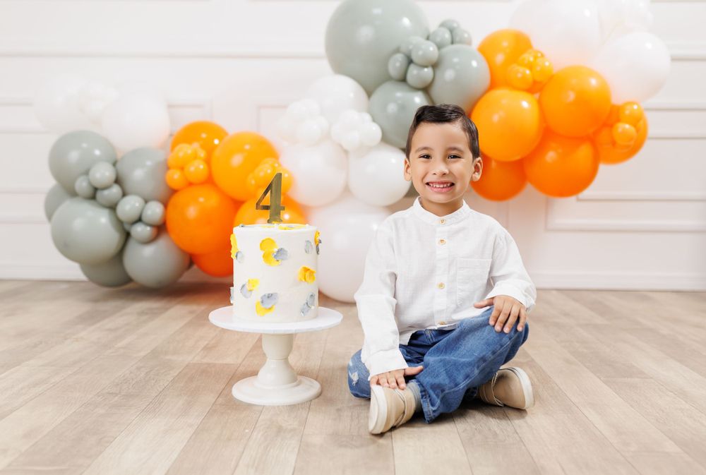 Birthday cake smash photo session with grey and orange balloon decorations.
