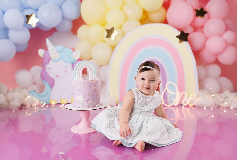 First birthday setup with pastel balloon arch and unicorn theme decorations.