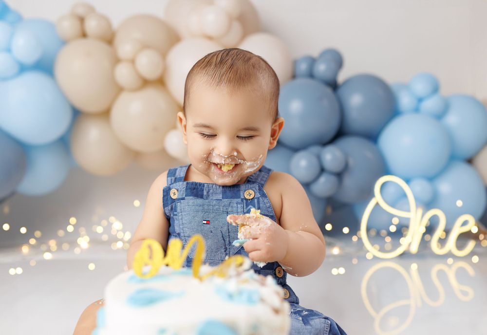 Birthday celebration with blue and neutral balloon garland and sparkly decorations.