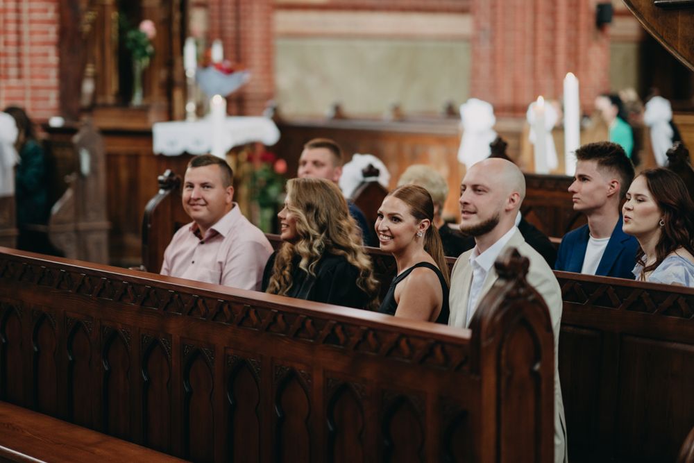 Wedding guests seated in wooden church pews during a ceremony.