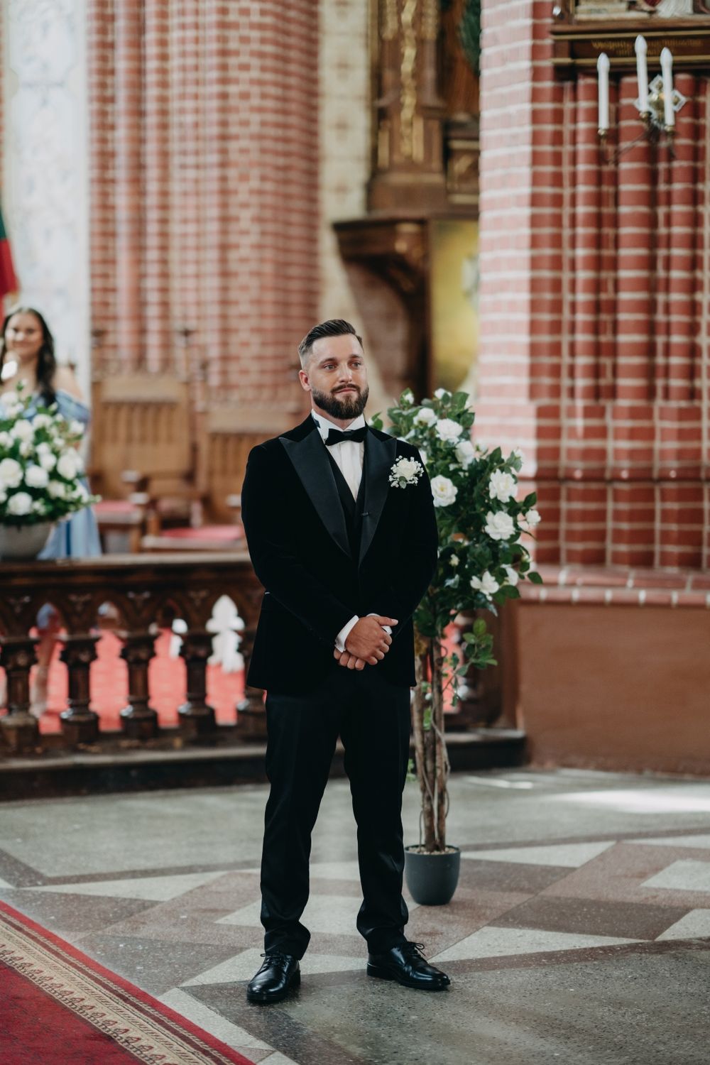 Elegant church interior with red brick columns and white floral arrangements.