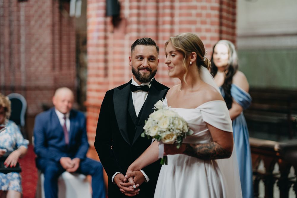 Wedding ceremony in a historic brick church with ornate architectural details.
