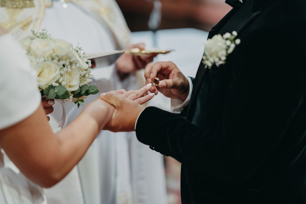 Close-up of hands exchanging rings during wedding ceremony.