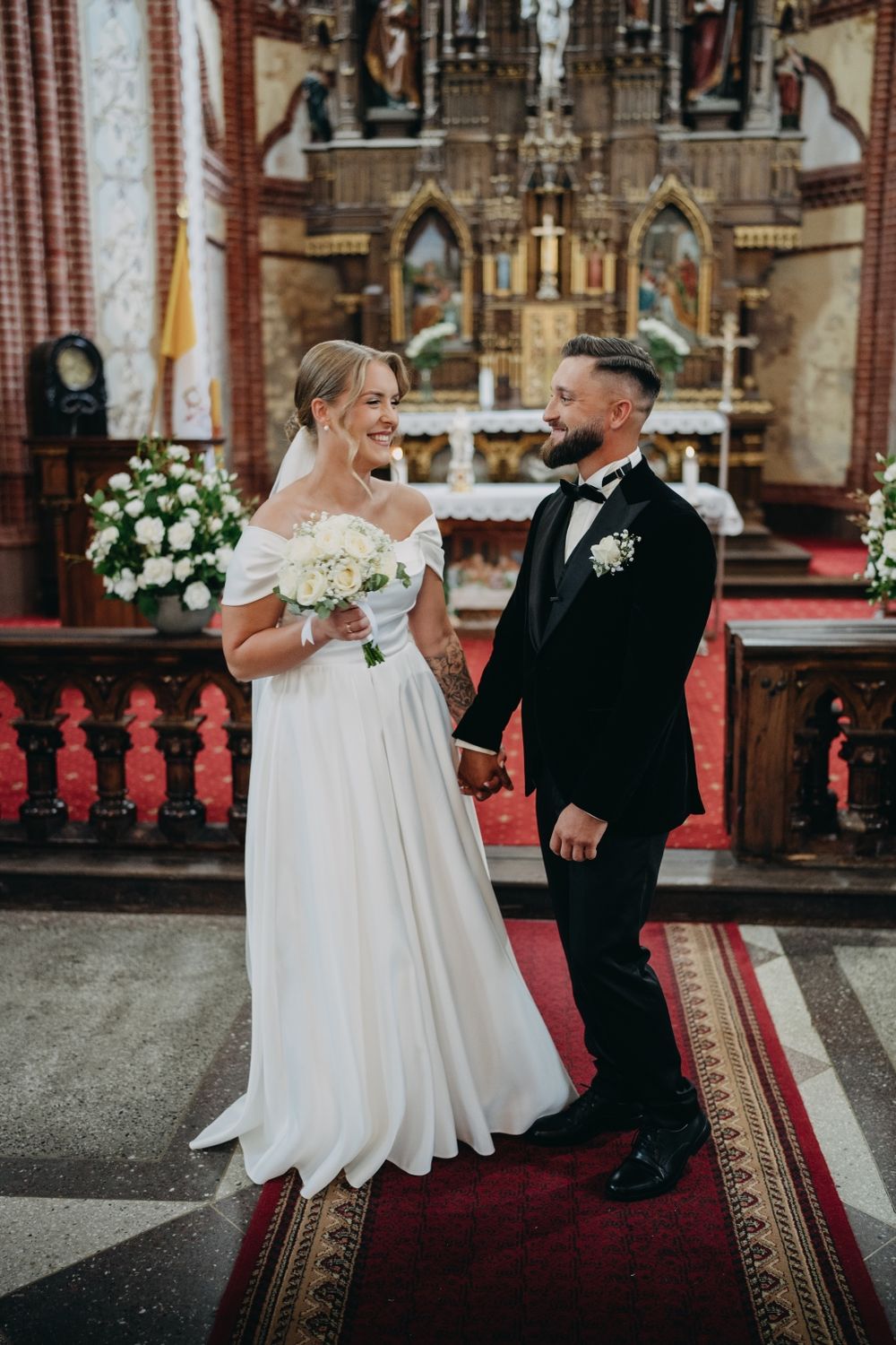 Wedding couple sharing a moment on red carpet in historic church interior.