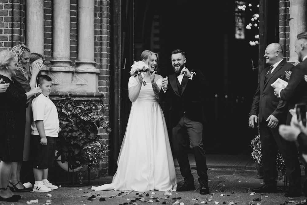 Black and white photo of wedding party outside historic church building.