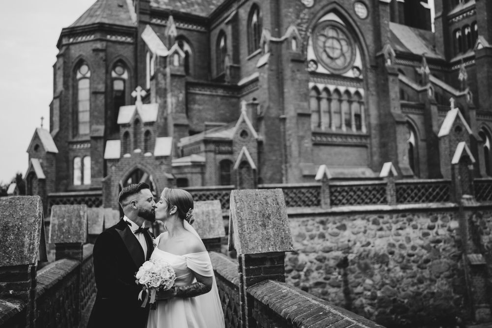 Wedding couple posing in front of historic red brick church architecture.