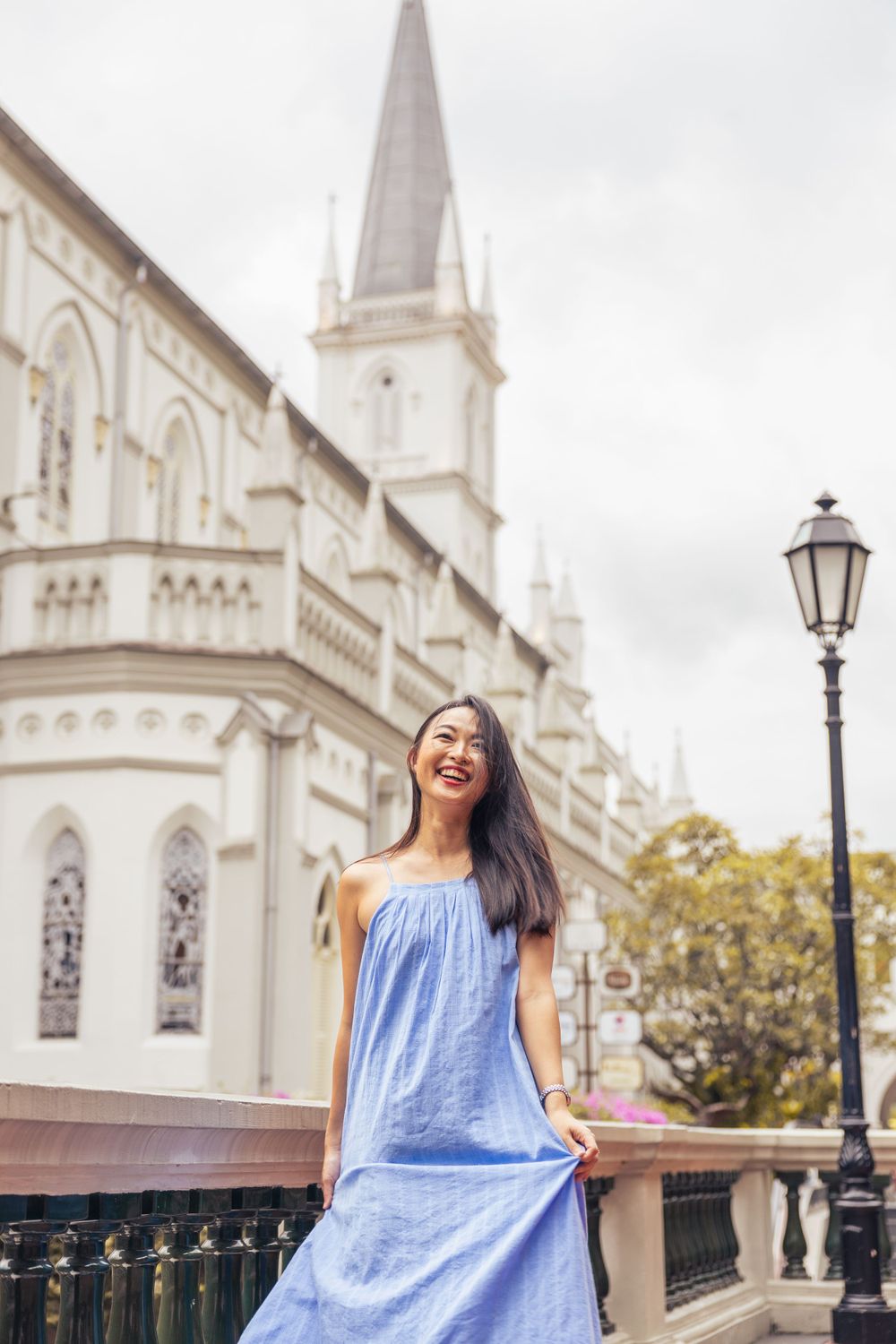 Elegant cathedral with white spire provides stunning backdrop for summery blue dress photo.