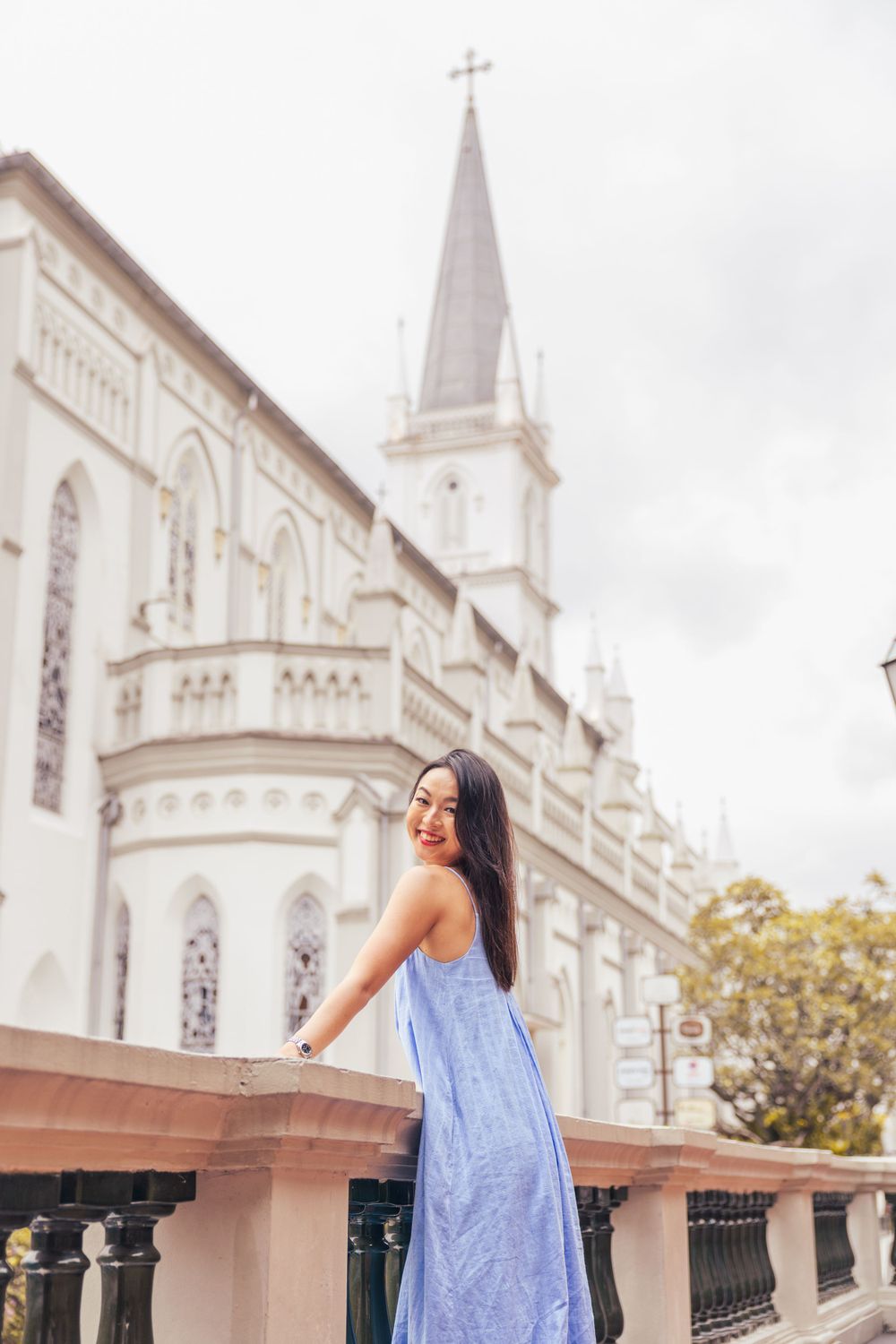 Flowing blue dress stands out against white church spire and architectural details in background.