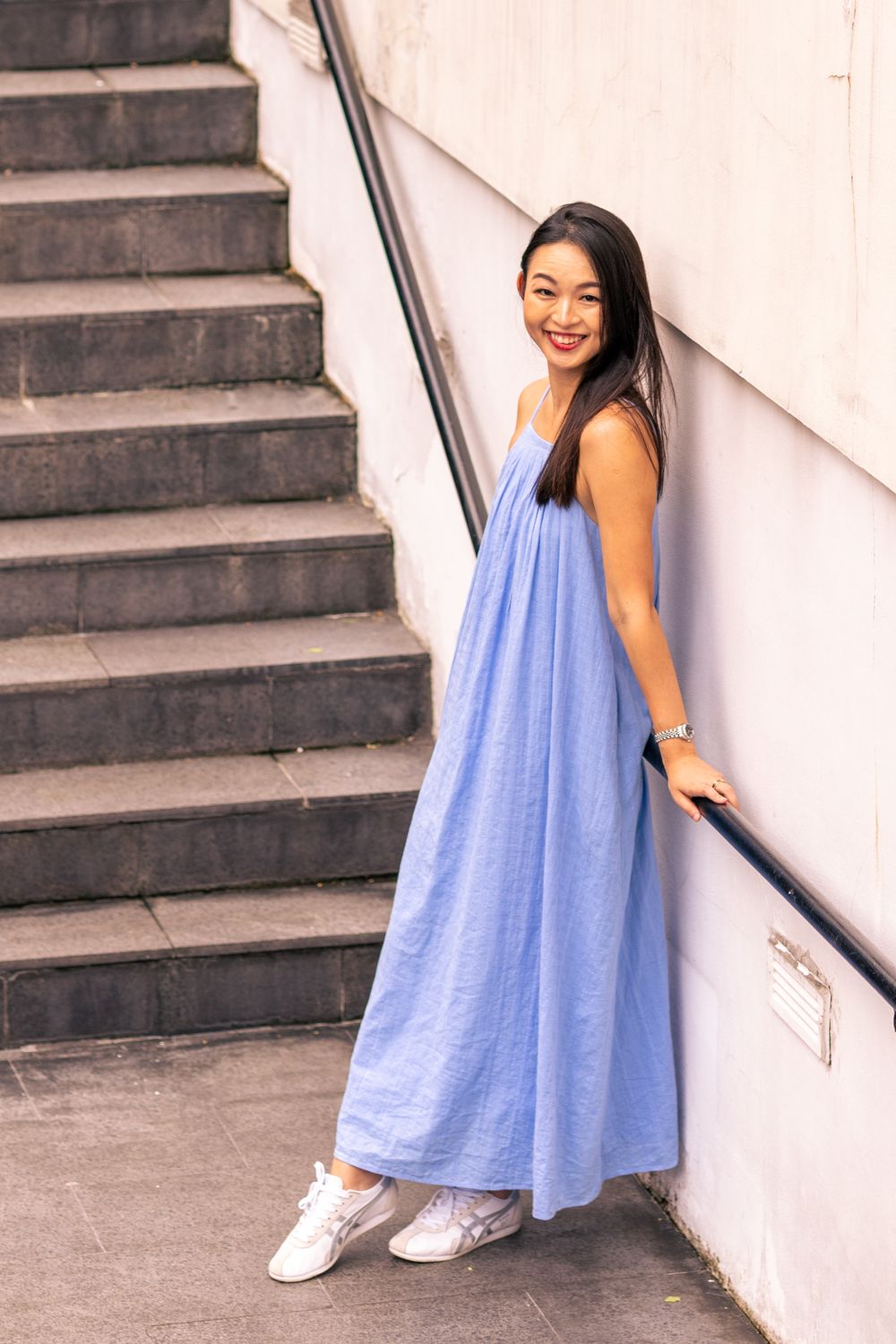 Casual blue maxi dress and white sneakers outfit photographed on concrete staircase.