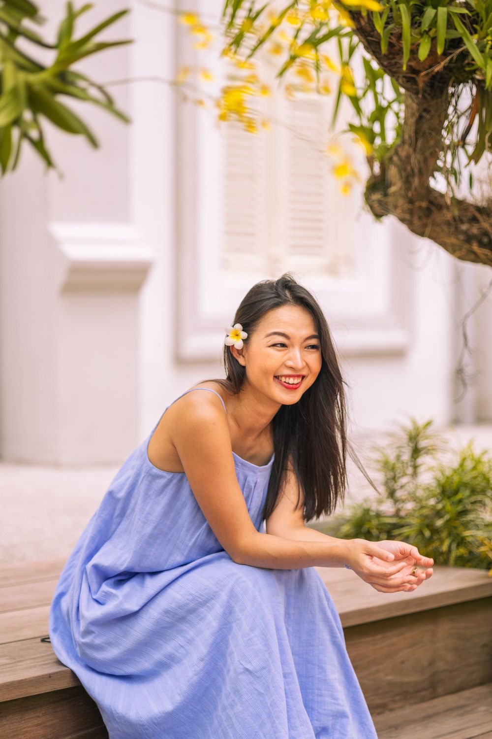 Casual blue sundress creates beautiful contrast with lush tropical garden and white architecture.