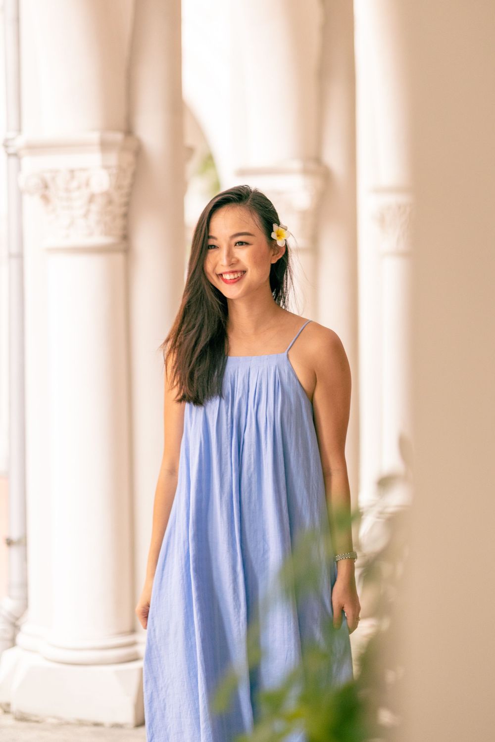 Airy blue maxi dress complements classic white colonnade and yellow flower accent.