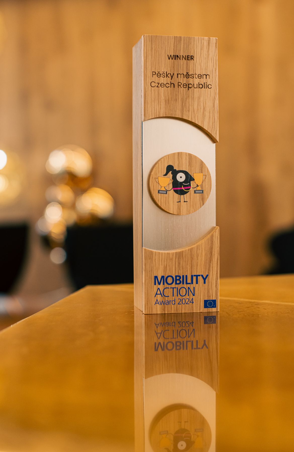 Wooden award trophies with mobility action text displayed on a warm wood surface.