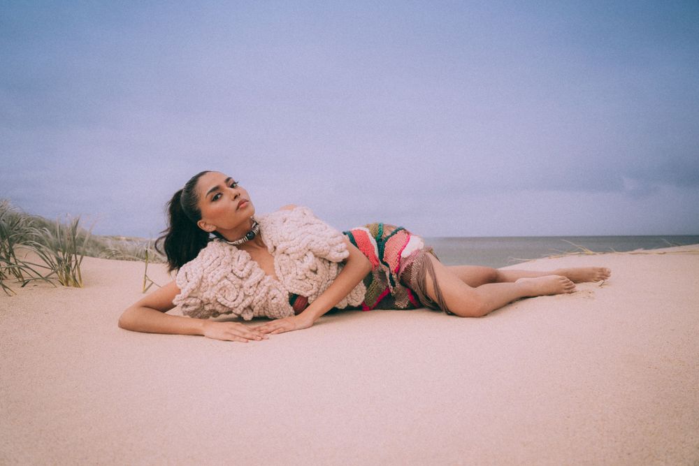 Dreamy beach portrait of person lying in sand wearing lace outfit.