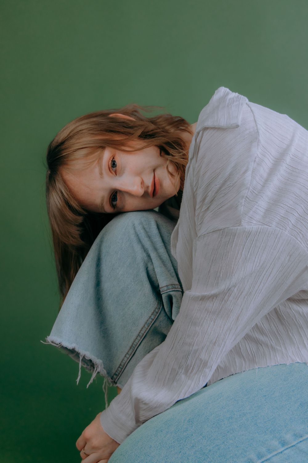 Artistic portrait series with reclining poses against green studio backdrop.
