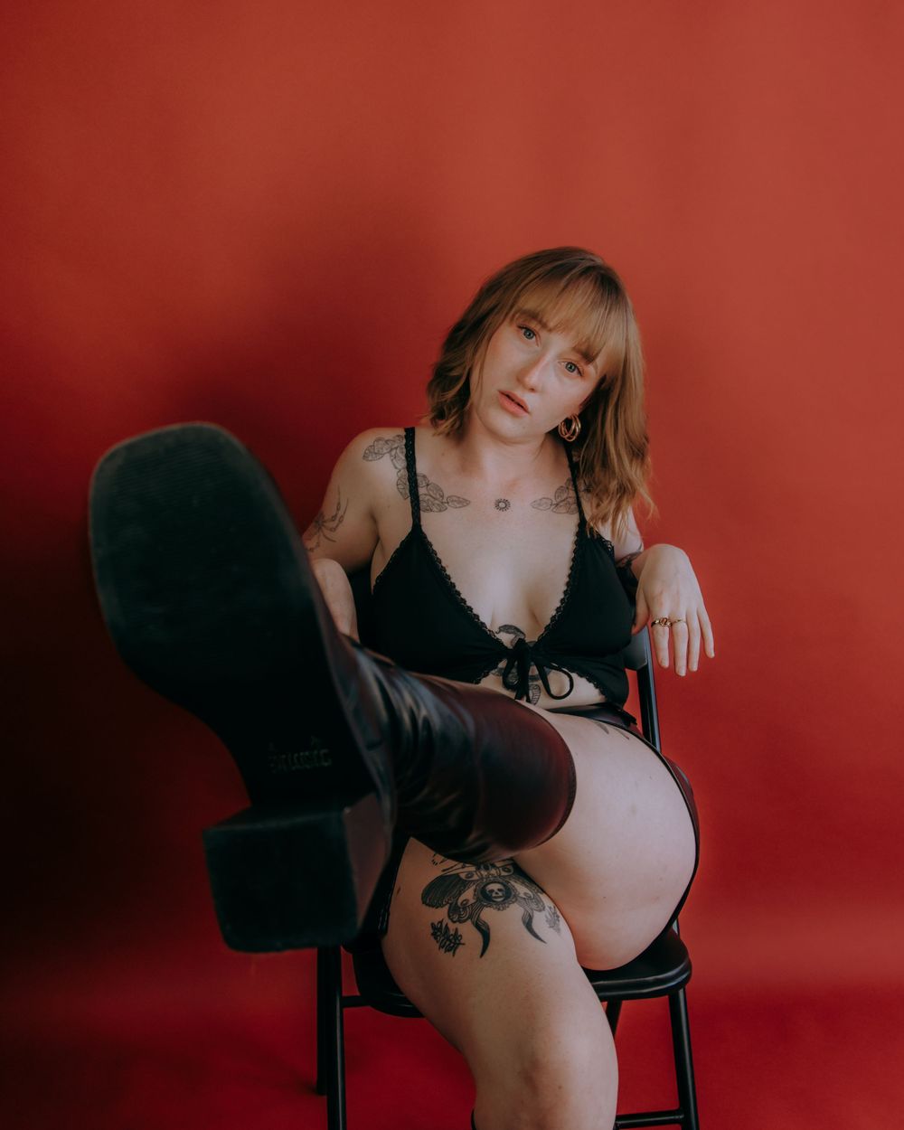 Intimate portrait session against red background with artistic lighting and poses.