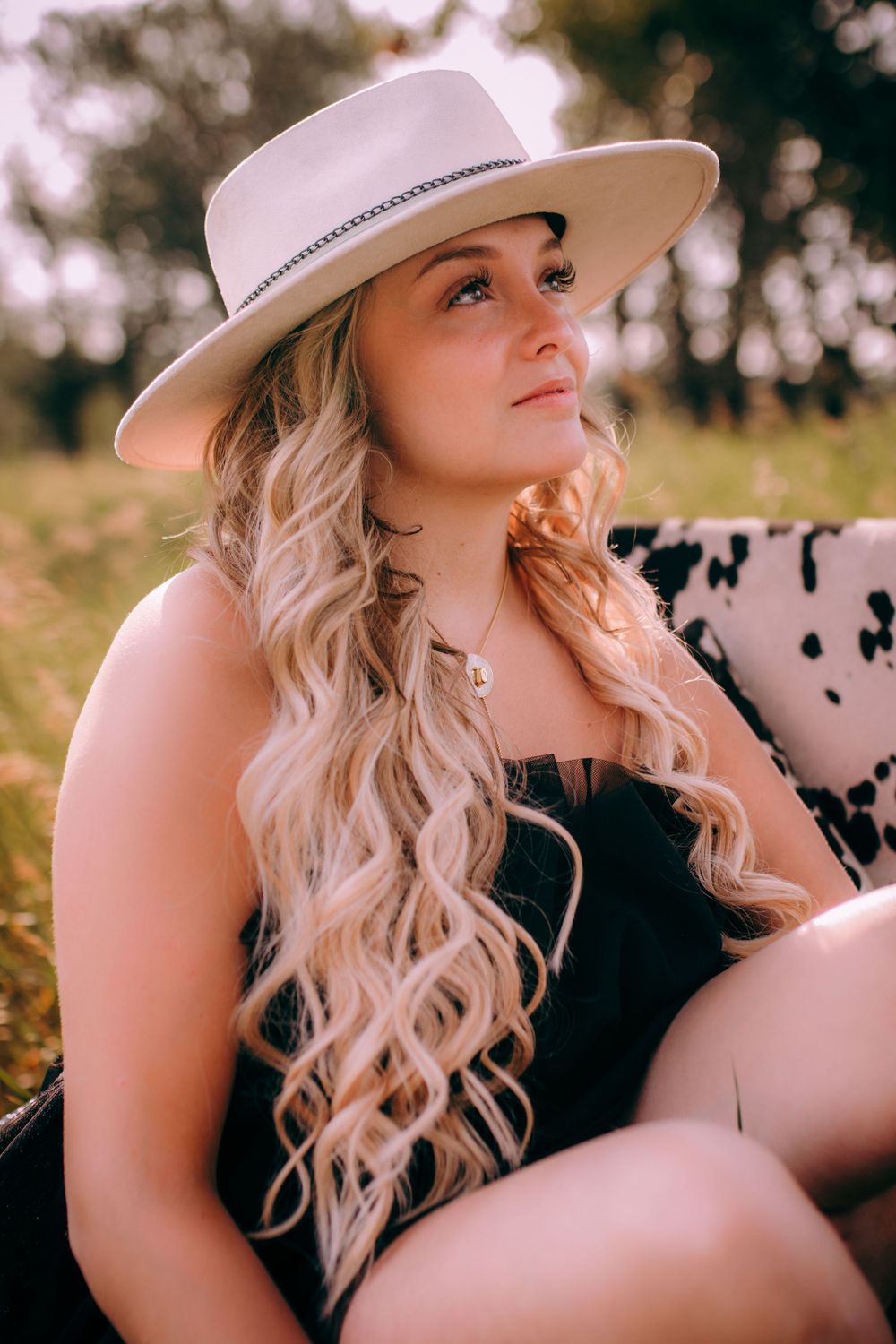 Western style portrait with white cowboy hat and wavy hair in natural setting.