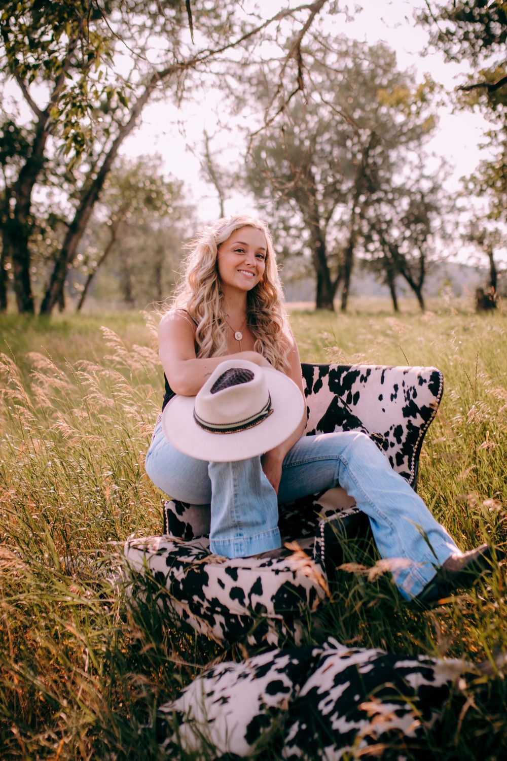 Country western style scene with cowhide pillows and hat in a golden meadow.