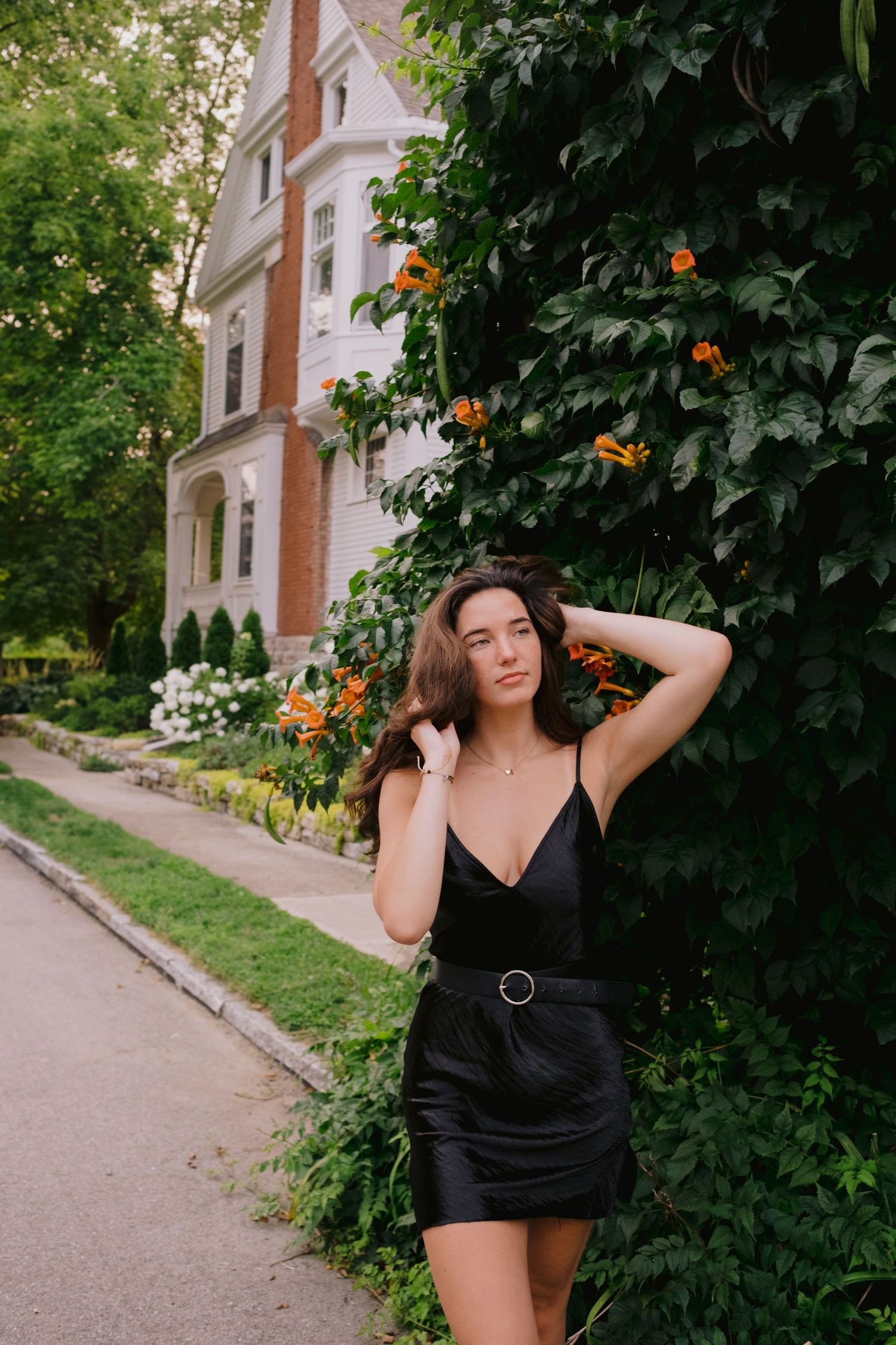 Fashion portrait against garden foliage and white brick Victorian architecture.