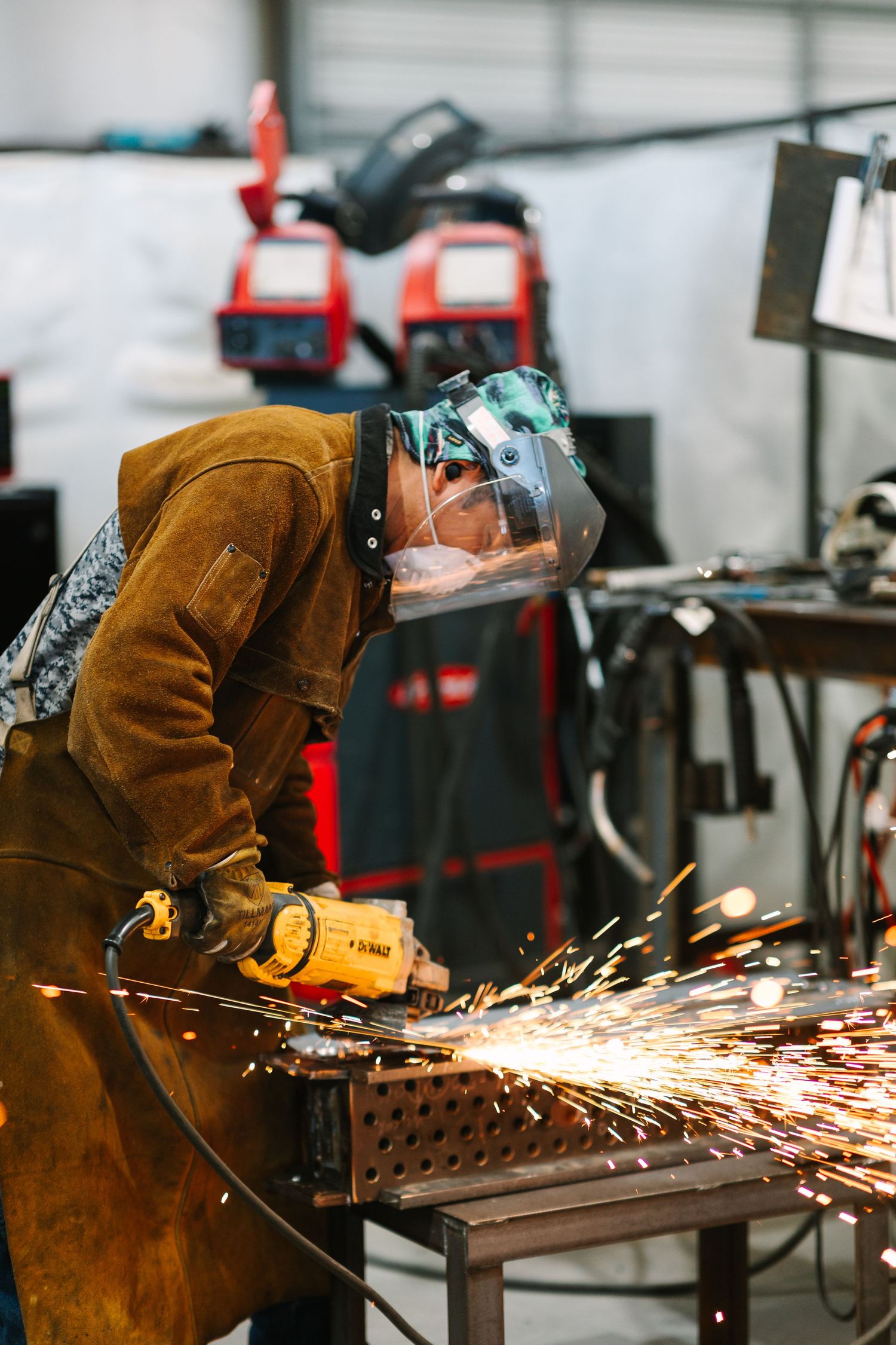 Welder in protective gear creating sparks while working with metal in workshop.