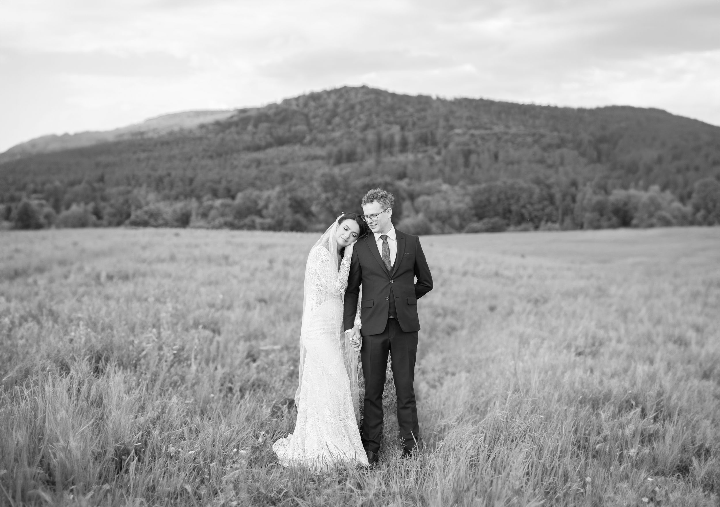 Black and white wedding portrait in a mountain meadow with scenic landscape.