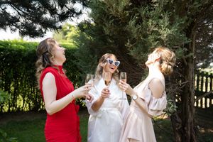 A group enjoying drinks and laughter at an outdoor gathering in a lush garden setting.
