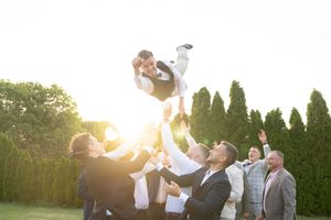Wedding guests celebrate with confetti and bubbles during a joyful outdoor ceremony at sunset.