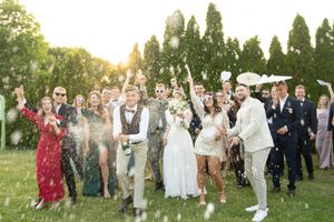 Wedding celebration in a garden setting with guests tossing confetti amidst golden hour sunlight.
