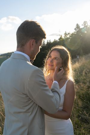 A couple shares an intimate moment in a sunlit meadow during their wedding photoshoot.