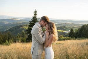 Romantic sunset portrait of newlyweds embracing in a golden mountain meadow.