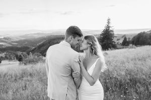 Black and white portrait of a couple sharing an intimate moment in a mountain field.
