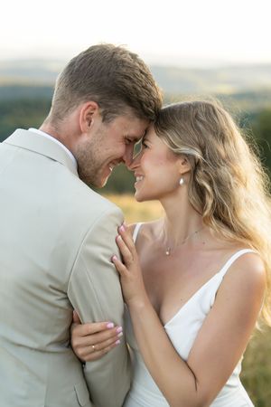 A romantic couple sharing intimate moments against a scenic outdoor backdrop at sunset.