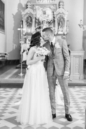 A black and white wedding portrait inside a church with ornate altar decoration.