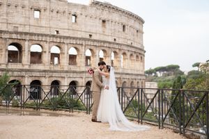 A wedding couple poses in front of the ancient Colosseum in Rome during a romantic photoshoot.