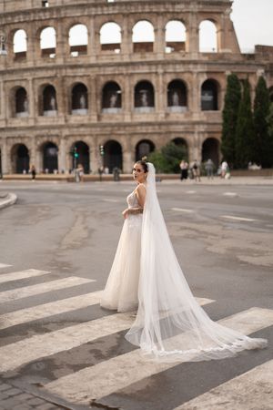 A flowing white wedding dress with a long veil photographed in sequence against the historic backdrop of the Roman Colosseum.