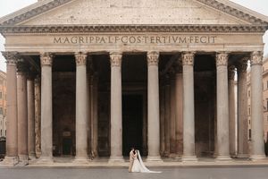 Wedding couple poses in front of the majestic columns of the Pantheon in Rome, Italy.