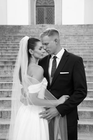A romantic wedding couple shares intimate moments on stone steps in a series of black and white photographs.