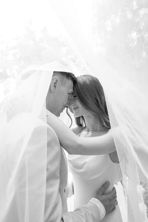 A romantic black and white wedding photo sequence showing a couple embracing under a flowing veil.