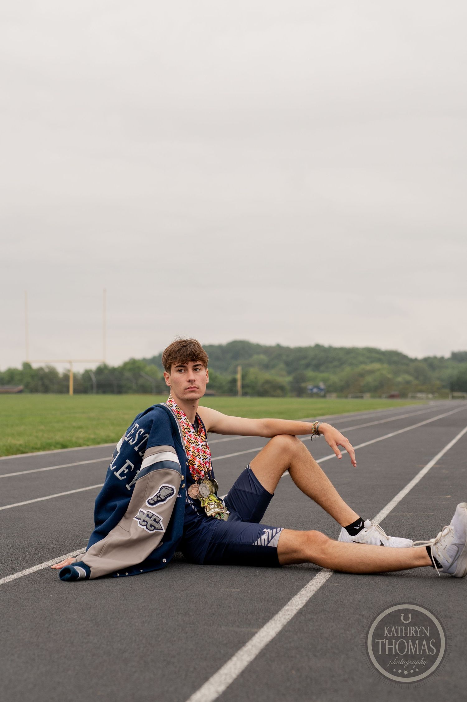 Runner relaxes on track wearing navy uniform and white shoes under cloudy skies.