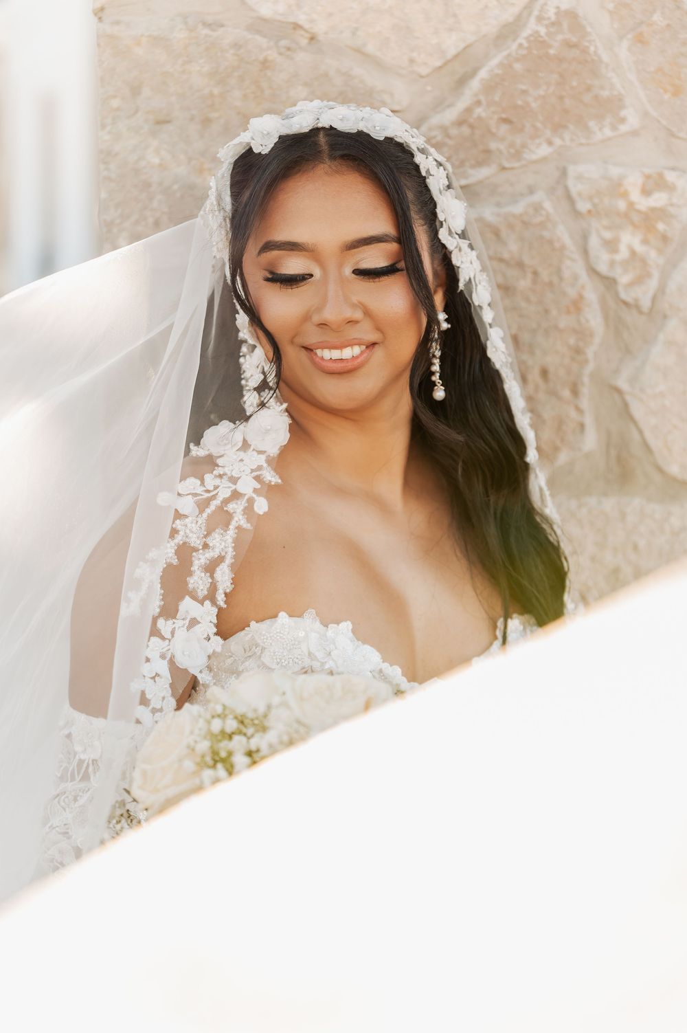 A bride wearing an elegant lace veil smiles softly in a series of romantic wedding day portraits.