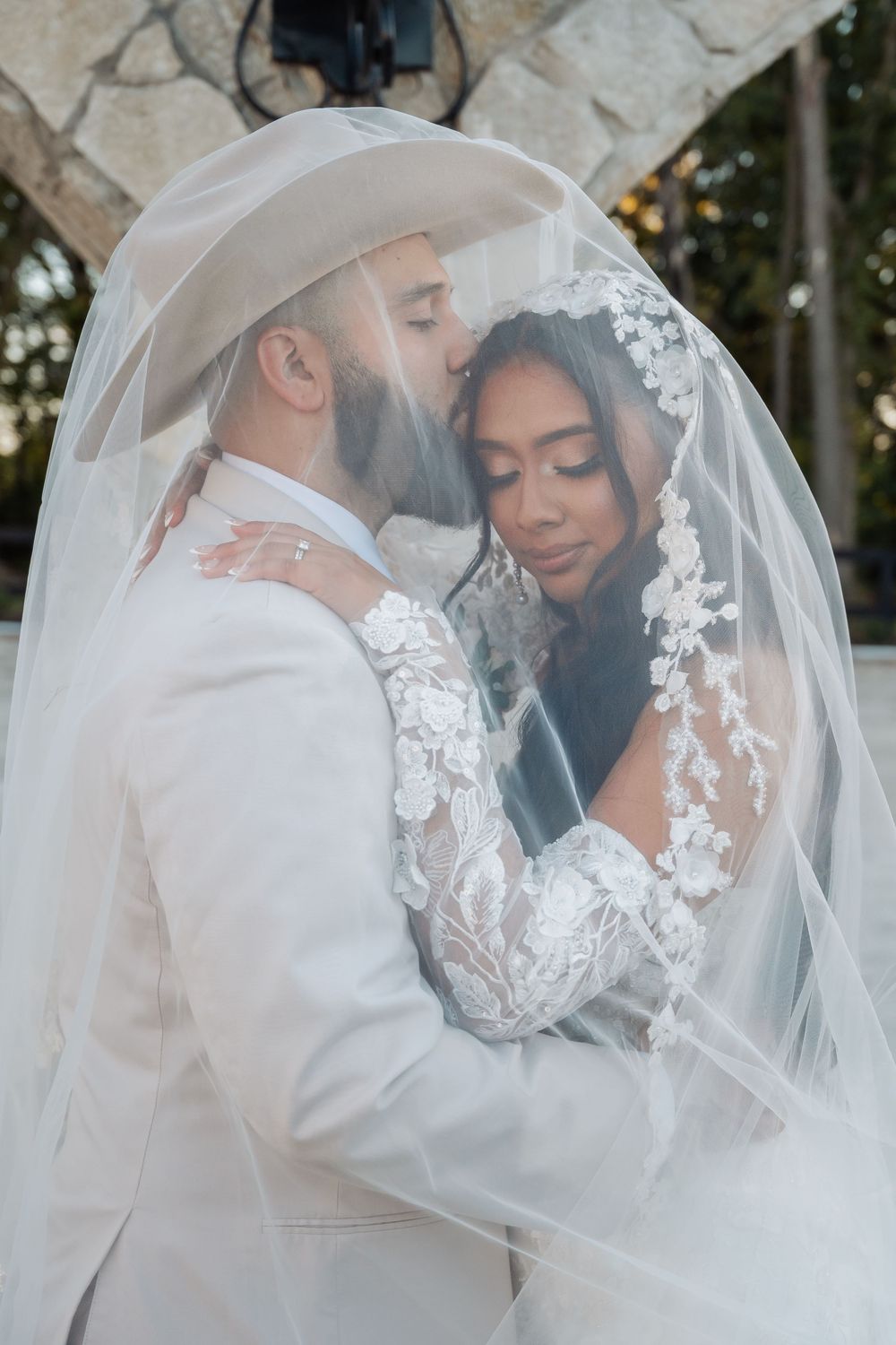A tender moment between newlyweds embracing under a delicate lace veil during their wedding ceremony.