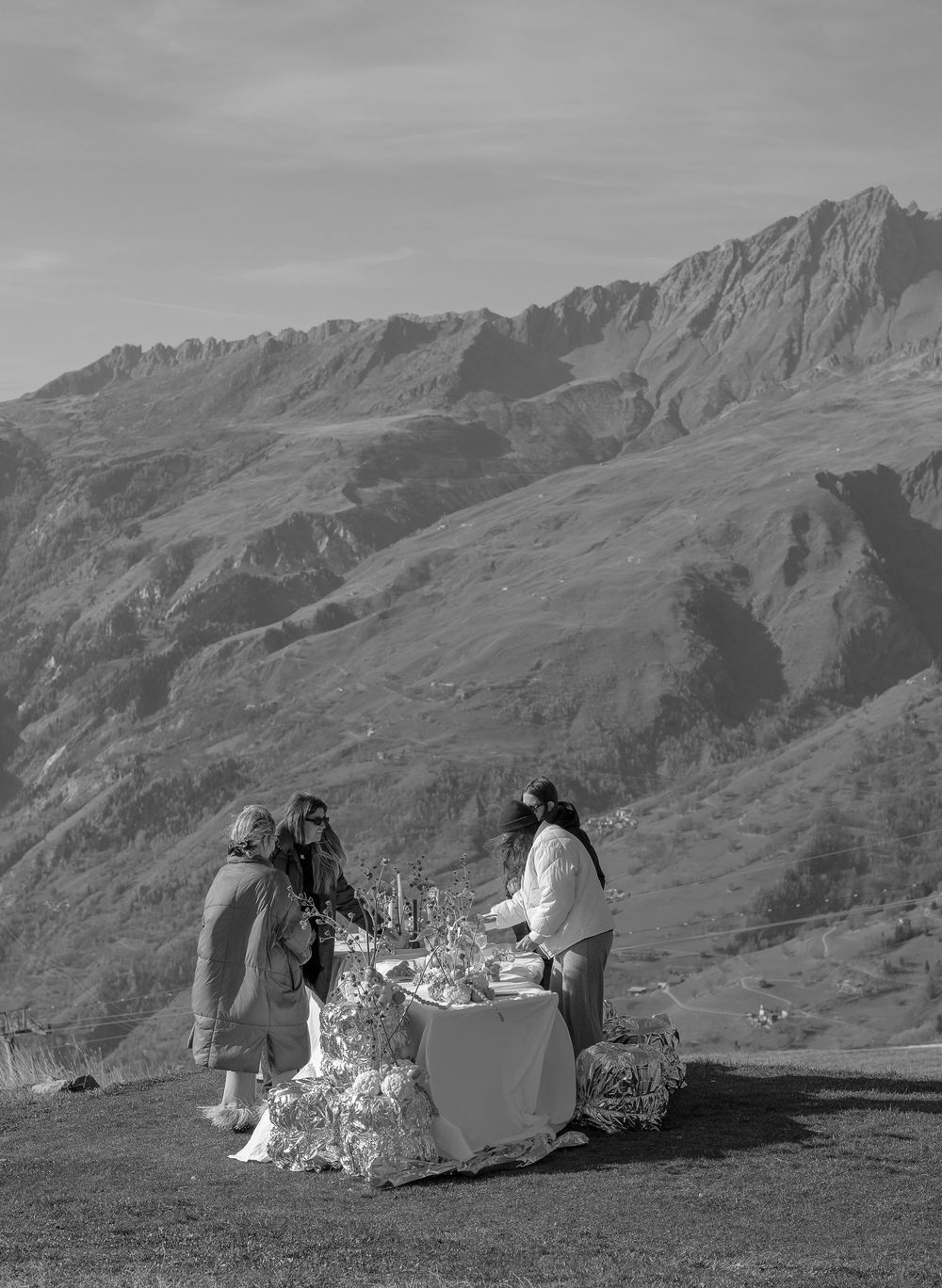 Picnic setting on a mountain ridge with dramatic Alpine peaks and valleys stretching into the distance.