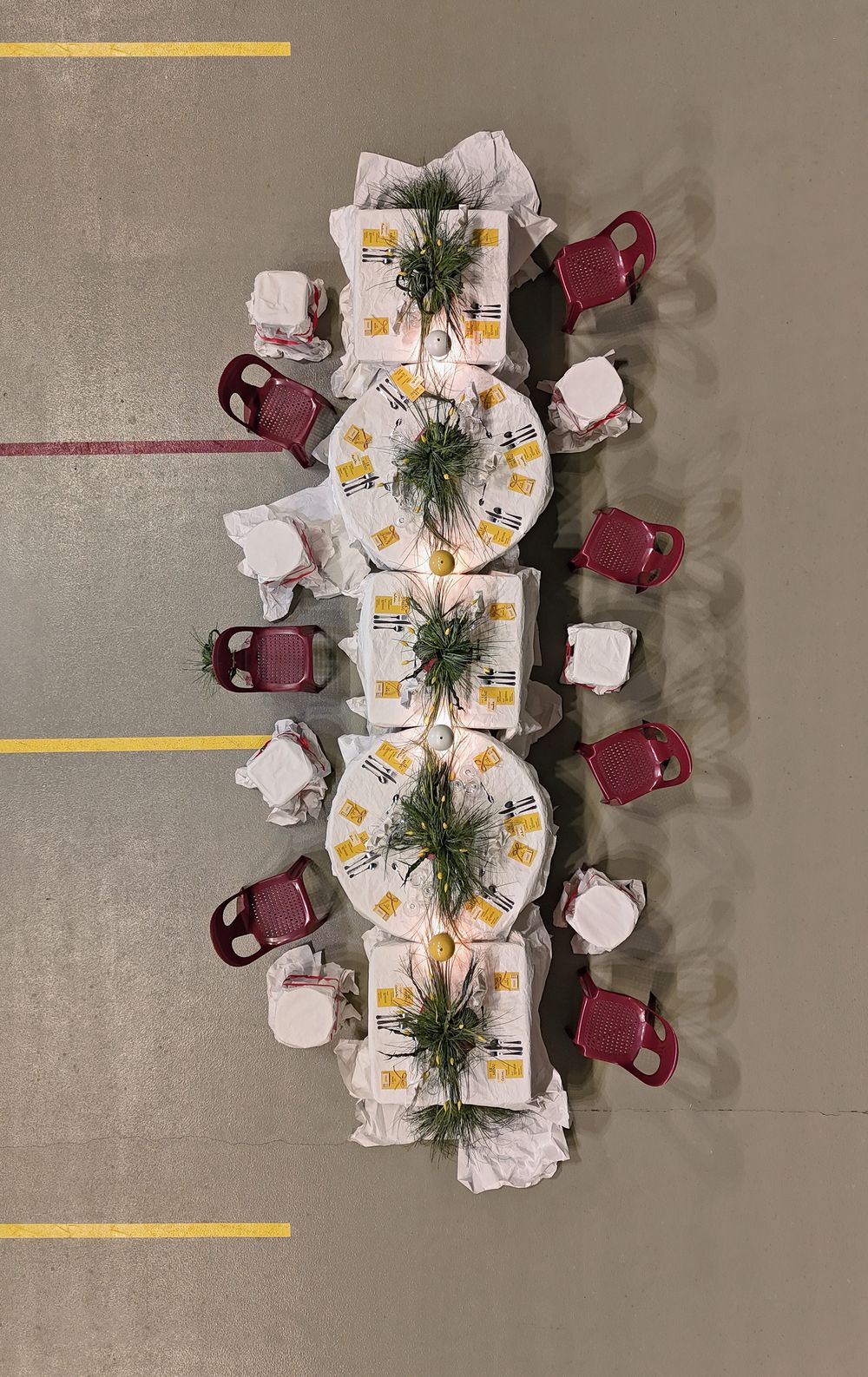 Overhead view of a long dining table with white tablecloth and burgundy chairs arranged in a modern setting.